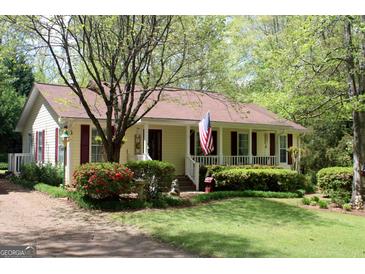 Charming single-story home with a cozy front porch, American flag and well-manicured landscaping at 206 Pine Cedar Cir, Brooks, GA 30205