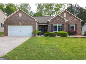 Charming brick home features a two-car garage and manicured front lawn with mature landscaping at 327 Viceroy Curv, Stockbridge, GA 30281