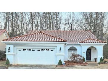 Charming single-story home featuring a red tile roof, arched window, and a two-car garage at 144 Garden Walk, Stockbridge, GA 30281