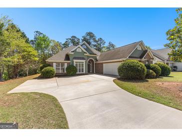 Inviting one story home boasts a well-manicured lawn, long driveway, two car garage, and a charming brick and stucco facade at 202 Willow Rock Pt, Fayetteville, GA 30215