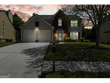 Charming two-story home boasts a well-maintained lawn, two-car garage and classic brick and siding facade at 340 Hammersmith Dr, Suwanee, GA 30024