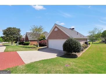 Charming brick home featuring an attached two-car garage and well-maintained landscaping under a clear blue sky at 1313 Jubilee Ln, Mcdonough, GA 30253