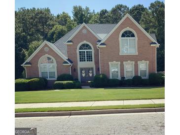 Charming brick home featuring a well-manicured lawn, manicured shrubbery, and a gray roof at 135 Danube Trl, Stockbridge, GA 30281
