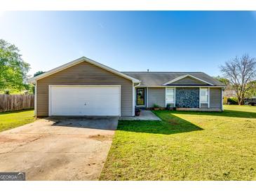 Charming single-story home featuring a two-car garage, stone accents, and a well-maintained lawn at 2582 Rosecommons Dr, Hampton, GA 30228
