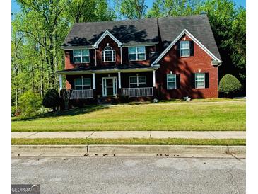 Charming two-story red brick home with a welcoming front porch and manicured lawn in a serene, wooded setting at 419 Tea Rose N Ln, Stockbridge, GA 30281