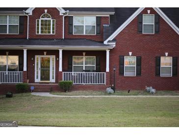 Traditional two story brick home with a cozy front porch and well manicured lawn at 419 Tea Rose N Ln, Stockbridge, GA 30281