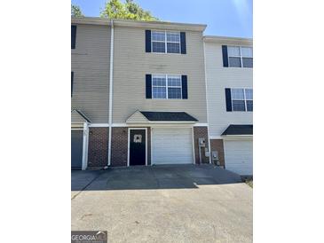 Two-story townhome with tan siding, brick accents, attached garage, and driveway at 23 Corinth Rd, Cartersville, GA 30121