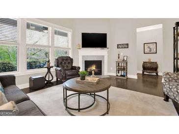 Comfortable living room featuring a fireplace, neutral tones, and a large window providing natural light at 5910 Stellata Cir, Cumming, GA 30028