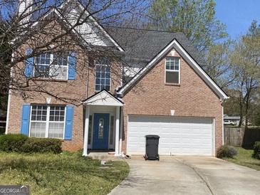 Charming two-story brick home featuring a welcoming blue door, shutters, and attached garage at 390 Hulan Way, Lawrenceville, GA 30044