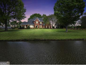 Stunning brick home with a well-manicured lawn and water view at dusk at 39 Gabrielle Ct, Stockbridge, GA 30281