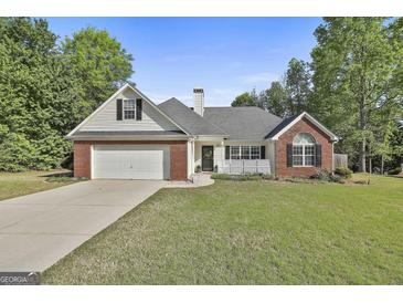 Charming single-story home with a brick facade, manicured lawn, and two-car garage at 140 Pecan Ridge Dr, Fayetteville, GA 30215