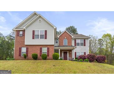 Two-story home featuring a mix of brick and siding, complemented by red shutters and manicured landscaping at 3156 Oak Ridge Ln, Loganville, GA 30052