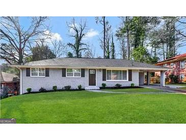 Charming one-story home with a gray painted brick exterior, well-manicured lawn, and covered parking at 3191 Gay Dr, Decatur, GA 30032