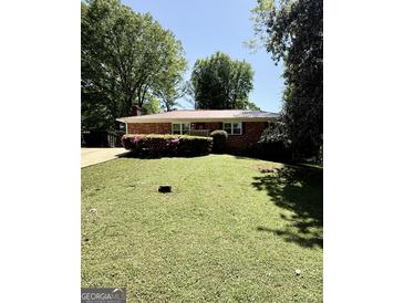 Charming brick ranch home with a well-manicured lawn, mature trees, and a metal roof at 1093 Grace Sw St, Mableton, GA 30126