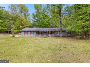 Quaint ranch home with light blue siding, red shutters and a well-manicured lawn surrounded by mature trees at 324 County Line Rd, Fayetteville, GA 30215