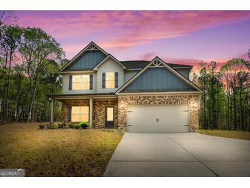 Charming two-story home with a brick facade, gray siding, and a two-car garage under a beautiful violet sky at 1011 Austin Rd, Ellenwood, GA 30294