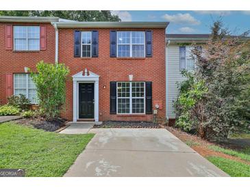 Charming brick townhome featuring black shutters, large windows, and a well-maintained front yard at 1372 Hollenbeck Ln, Riverdale, GA 30296