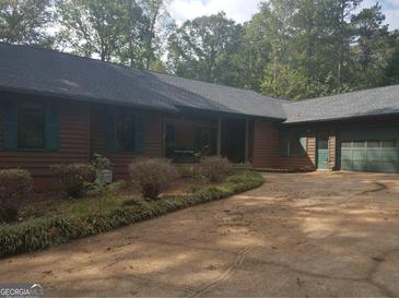 Ranch home with two car garage, brown siding, and mature landscaping at 2467 Highway 138 Sw, Conyers, GA 30094