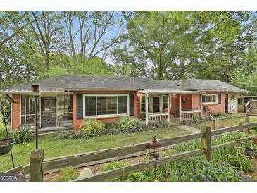 Charming brick home with a cozy front porch, landscaped yard, and a rustic wooden fence at 2008 Highway 92 S, Fayetteville, GA 30215