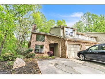 Two-story brick home featuring an attached garage, arched entryway, and mature trees at 675 Granby Hill Pl, Alpharetta, GA 30022