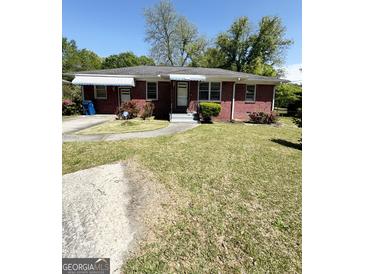 Charming brick home featuring a well-maintained lawn and manicured landscaping at 6718 Delta Dr, Riverdale, GA 30274