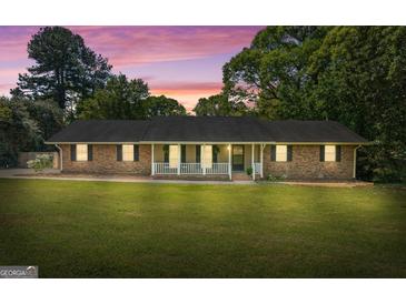 Charming brick home featuring a well-manicured lawn and a welcoming front porch with white railings at 25 Hickory Dr, Stockbridge, GA 30281