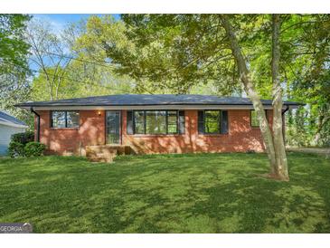 Charming red brick home with well-maintained lawn and mature trees shading the front yard at 172 W Campbellton St, Fairburn, GA 30213