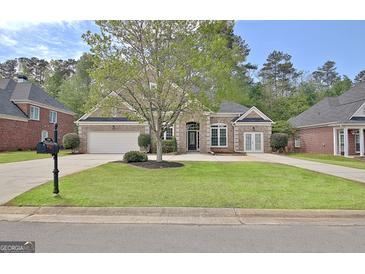 Charming brick home with a well-manicured lawn, two-car garage, and inviting front entrance at 1619 Cascade Overlook, Peachtree City, GA 30269