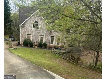 Charming two-story brick home featuring a well-manicured lawn and lush, mature landscaping at 4588 Carissa Ct, Ellenwood, GA 30294