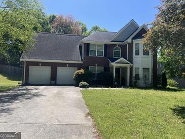 Charming two-story brick home featuring an attached two-car garage and mature landscaping in a suburban setting at 345 S Magnolia Se Walk, Atlanta, GA 30349