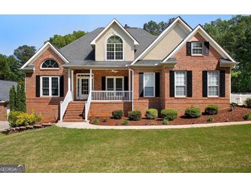 Charming brick home featuring a covered front porch, manicured landscaping, and black shutters at 1108 Sequoia Trl, Mcdonough, GA 30252