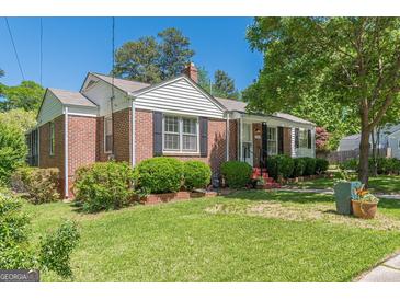 Charming brick home featuring a well-maintained lawn, mature trees, and classic black shutters at 1325 E Forrest Ave, East Point, GA 30344