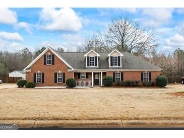 Charming brick home featuring dormer windows, black shutters, and manicured landscaping at 115 Stewart Hollow Ln, Covington, GA 30016