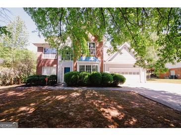 Charming two-story home with brick and siding, a blue front door, and well-manicured landscaping at 1417 Se Pickett'S Ct, Conyers, GA 30013