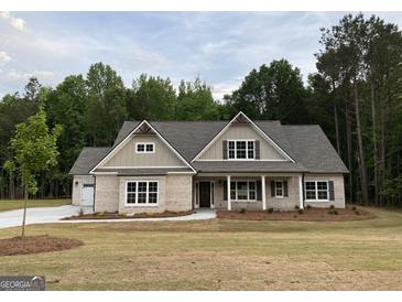 Charming, single-story brick home featuring a covered front porch, attached garage, and professionally landscaped front yard at 2109 Ella Springs Dr, Covington, GA 30014