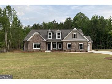 Beautiful brick home with a manicured lawn and a three-car garage at 2113 Ella Springs Dr, Covington, GA 30014