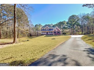 Beautiful two-story home with a brick facade, large front yard, and long driveway at 671 Ellison Rd, Tyrone, GA 30290