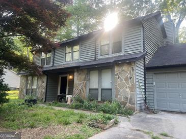 Charming two-story home with stone accents and a cozy front porch, complemented by mature trees and a one-car garage at 5364 Kelleys Creek Dr, Stone Mountain, GA 30088