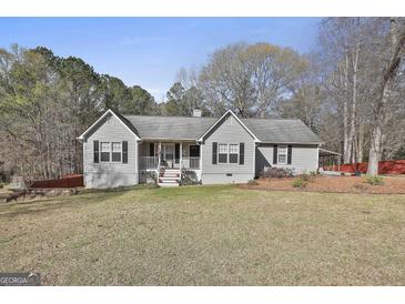 Charming single-story home featuring gray siding, black shutters, and a cozy front porch with an American flag at 100 Rockland Trl, Sharpsburg, GA 30277