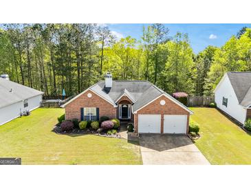 Charming brick home featuring a well-manicured lawn and a two-car garage at 11970 Fairway Overlook, Fayetteville, GA 30215