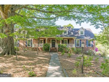 Charming brick home featuring a welcoming front porch and well-manicured landscaping under the shade of mature trees at 13819 Woolsey Rd, Hampton, GA 30228