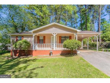 Charming single-story home with a covered porch and a carport, surrounded by lush greenery and a well-maintained lawn at 842 Brighton Dr, Lawrenceville, GA 30043