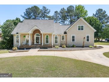 Stunning home featuring a stone archway entrance, manicured lawn, and a circular driveway at 207 Jamestown Ave, Jonesboro, GA 30236