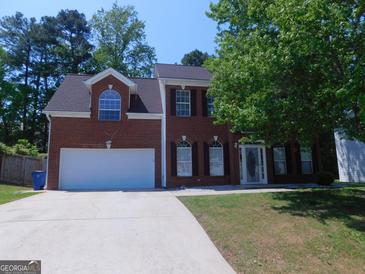 Charming two-story brick home featuring a well-manicured lawn and attached garage at 7541 Coddington Ct, Riverdale, GA 30274