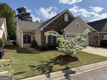 Charming home with stone accents, manicured lawn, and a blossoming tree in the front yard at 203 Collierstown Way, Peachtree City, GA 30269
