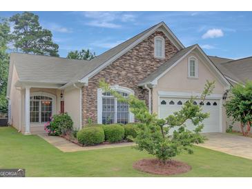 Charming home exterior with stone accents, two-car garage and a well manicured lawn at 203 Collierstown Way, Peachtree City, GA 30269