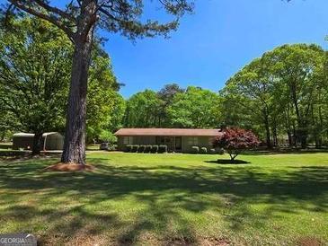 Charming ranch-style home with a lush green lawn and mature trees creating a serene landscape at 1710 Crumbley Rd, Mcdonough, GA 30252