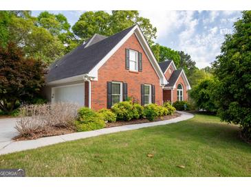 Charming brick home featuring a well-manicured lawn, black shutters, and a convenient two-car garage at 1270 Tribble Walk Ct, Lawrenceville, GA 30045