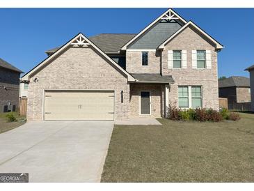 Beautiful two-story brick home with a two car garage, manicured lawn, and neutral color palette at 169 Cabin Way, Hampton, GA 30228