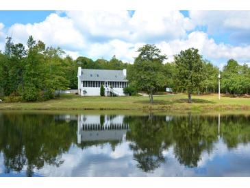 Scenic home exterior reflected in a serene pond surrounded by lush greenery and a bright, cloudy sky at 301 Spruill Bridge Rd, Temple, GA 30179